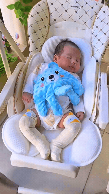 Bebê deitado usando a Almofada Calmante Baby, com a mão apoiada sobre o corpo